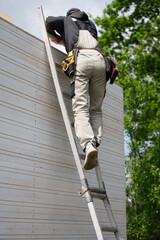 A worker climbs up a ladder while building a gazebo.