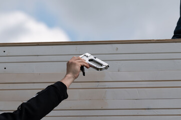Workers hand staplers to each other at a construction site.