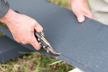 A man cuts a metal sheet with metal shears.