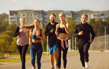 Group of sporty smiling people in sportswear jogging together in the city park. Friends running...