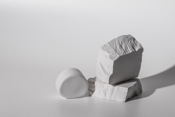 Podium of plaster white stones on light background.Minimal empty product presentation demonstration...