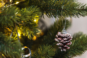 A Christmas tree toy, a pine cone, hangs on a sparkling tree. festive background for New Year or Christmas.