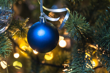 Blue Christmas tree ball hangs on a sparkling tree. festive background for New Year or Christmas.