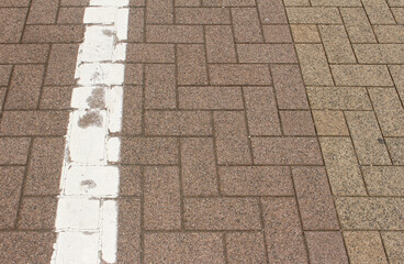 Texture of square paving tile. Pattern of brown and beige sidewalk tiles with a white line in the...