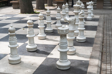 Giant chess pieces on a chessboard in a street square.