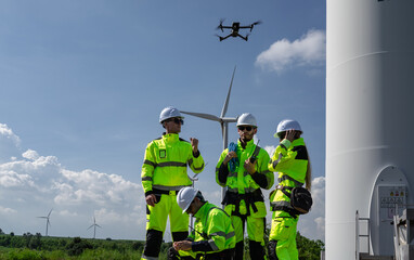 Maintenance engineer team standing at windmills at wind turbine farm. Group of people wear safety...