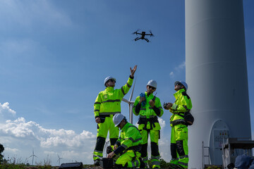 Maintenance engineer team standing at windmills at wind turbine farm. Group of people wear safety...