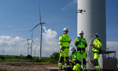 Maintenance engineer team standing at windmills at wind turbine farm. Group of people wear safety...
