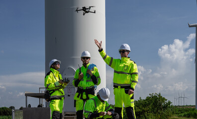 Maintenance engineer team standing at windmills at wind turbine farm. Group of people wear safety...