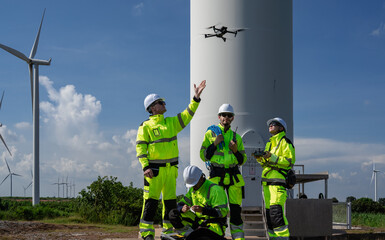Maintenance engineer team standing at windmills at wind turbine farm. Group of people wear safety...