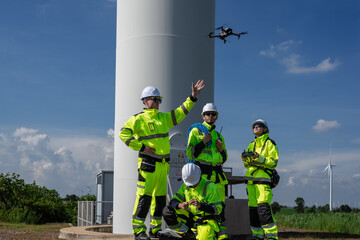 Maintenance engineer team standing at windmills at wind turbine farm. Group of people wear safety...