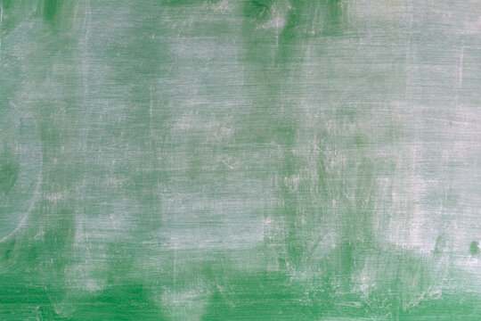 Green chalkboard with visible chalk marks and smudges, commonly found in classrooms or educational settings, ready to be written on or used for presentations and lessons.