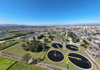 Visão aérea grande angular de uma indústria de saneamento com tanques e vegetação ao redor