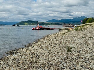 fishing village in norway Rocky shore with boats docked on a calm lake, surrounded by hills and...