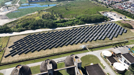 Visão aérea de painéis solares fotovoltaicos instalados em área industrial, destacando o uso de...