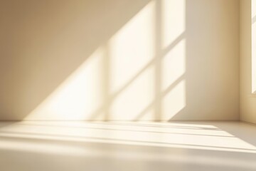 Sunlight streams through a large window, casting soft, warm shadows on a minimalistic beige wall and floor in an empty room.