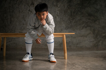 A boy in fencing gear sitting on a bench, ready for the épée competition
