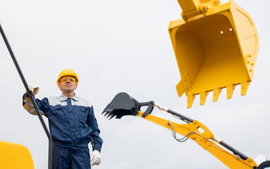 Engineer adult man in uniform and hard hat on background excavator construction site, industry...