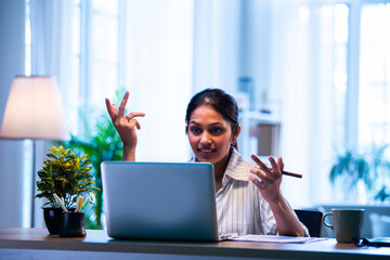 Indian executive uses laptop and headphone for remote video call at home or office workspace