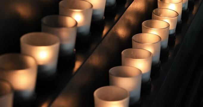 Memorial candles flicker in dark room religion symbol. Remember and sorrow for those who have passed and died before. Religion and faith in church and cathedral. 4K HD video footage.
