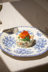 Portion of gourmet olivier salad with salmon on white background