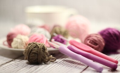 Clews of yarn wool balls on the plate and crochet hooks photo 