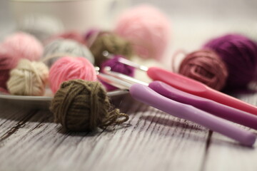 Clews of yarn wool balls on the plate and crochet hooks photo 
