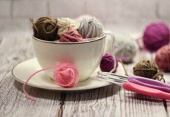 A cup and a saucer with clews balls of yarn wool and crocheted blanket handmade craft bright photo	
