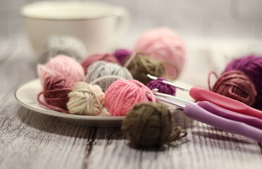 Clews of yarn wool balls on the plate and crochet hooks photo 