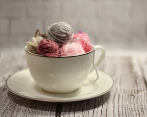 A cup and a saucer with clews balls of yarn wool and crocheted blanket handmade craft bright photo	
