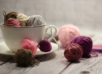 A cup and a saucer with clews balls of yarn wool and crocheted blanket handmade craft bright photo	
