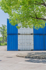 Blue and white container under green trees