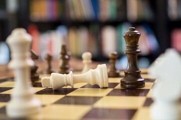 Black queen killing white king in close-up on traditional chess board