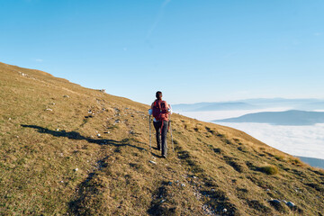 A female mountaineer, equipped with professional gear, enjoys the thrill of her climb as she...
