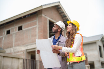 Construction teamwork man and woman engineers with helmets discussing plan blueprint indoors site.
