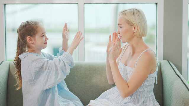 Playful Mother and daughter enjoying clap hands game bonding fun happy family time indoors.