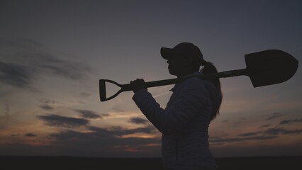silhouette of a senior farmer with a shovel at sunset, farming, small business of a gardener, the concept of an american work on plantation, an agronomist in a rural land of the land goes to dig soil.