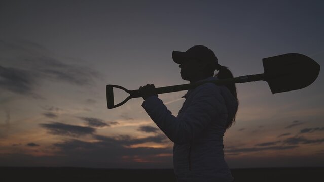 silhouette of a senior farmer with a shovel at sunset, farming, small business of a gardener, the concept of an american work on plantation, an agronomist in a rural land of the land goes to dig soil.