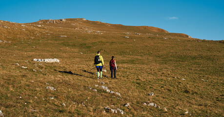 Couple hikers trek up a rocky mountain trail, enjoying a scenic view above the clouds, with...