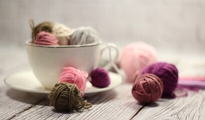 A cup and a saucer with clews balls of yarn wool and crocheted blanket handmade craft bright photo	

