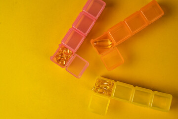 Organizers for nutritional supplements. Multicolored organizers with yellow Оmega 3 or vitamin D...