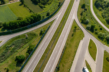 Top down view of empty multilane expressway and exit ramp surrounded by summer greenery, road design and infrastructure concept