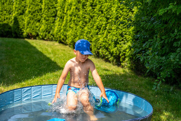 Young boy splashing in small backyard pool during sunny day surrounded by green bushes, summer leisure and childhood joy