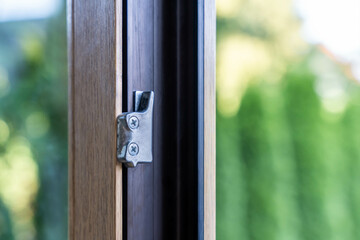 Close-up of window locking mechanism on wooden frame with green garden background, home security and design