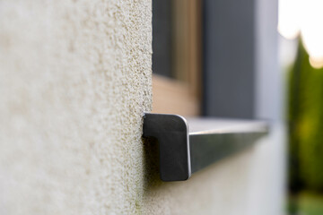 Wall-mounted plastic bracket under window ledge on building facade, close-up architecture detail highlighting structural support hardware
