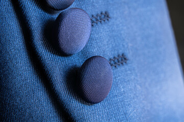 Macro shot of blue textile buttons stitched onto garment fabric surface with elegant shadow play and texture focus
