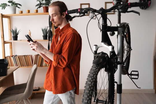 young man repair the bicycle using smartphone looking learning video online at home. - Powered by Adobe