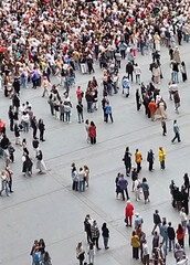 Aerial view of large crowd of people standing in small groups on urban square