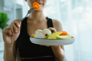 A woman enjoys a fresh, healthy salad made with organic vegetables at home, promoting a balanced...