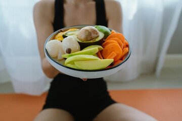 A woman enjoys a fresh, healthy salad made with organic vegetables at home, promoting a balanced...